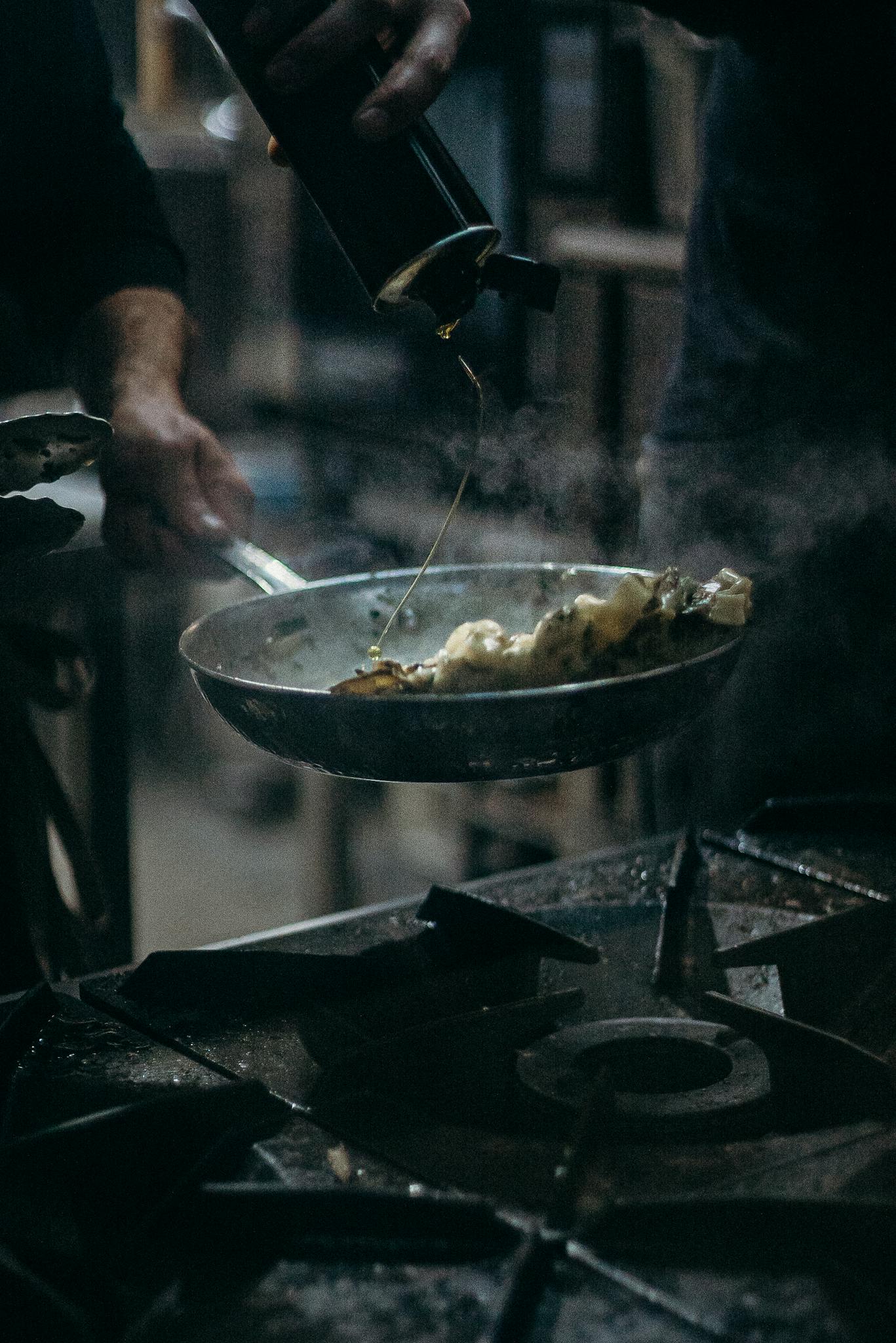 A chef pours oil into a hot frying pan, sizzling with delicious food. A glimpse into culinary artistry.